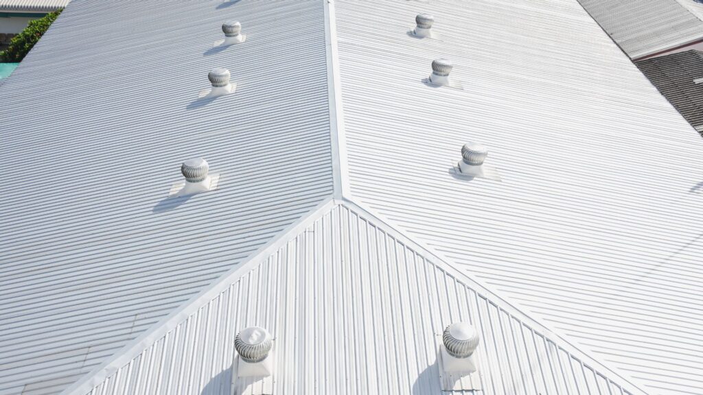 Aerial view of a white, gable-style metal roof with multiple vent structures.